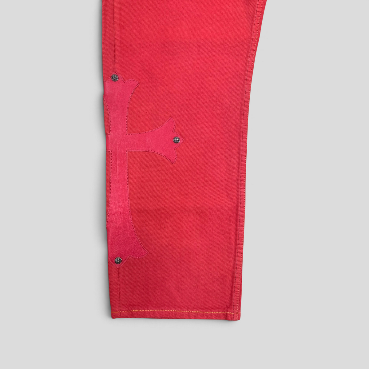 CLB XXIII Chrome Hearts red cotton jeans featuring a large leather cross patch with silver hardware detailing.