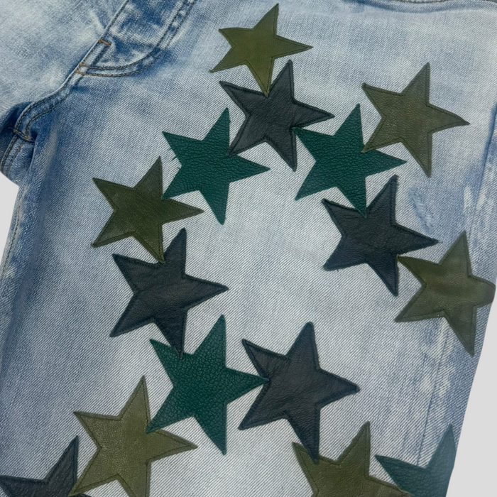 CLB XXIII Amiri light indigo denim jeans featuring green and dark green leather star patches in a circular pattern.