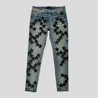 CLB XXIII Amiri Chemist star patch jeans in clay indigo denim with black star appliqués and distressed detailing.