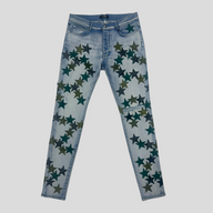 CLB XXIII Amiri Chemist light indigo denim jeans featuring dark green star patches and a slim fit design.