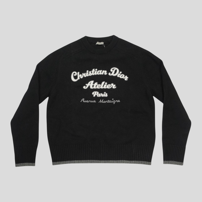 CLB XXIII black virgin wool sweater featuring white Christian Dior Atelier embroidery and ribbed grey hem detail.