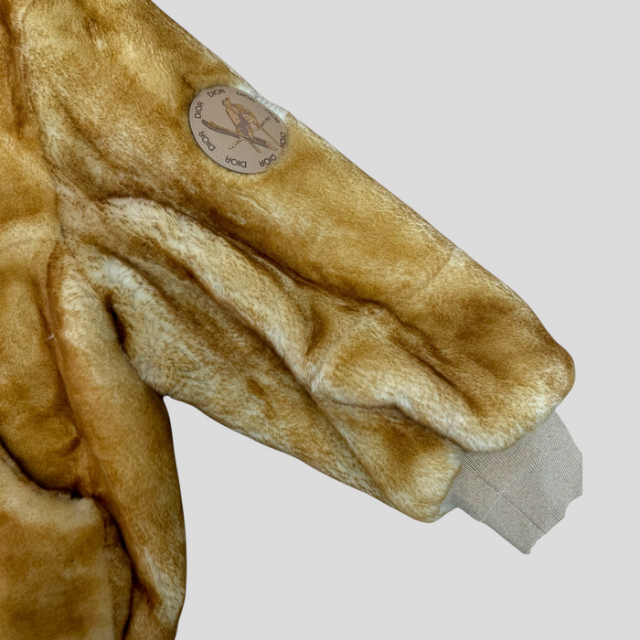 CLB XXIII Dior lamb fur coat sleeve featuring a circular logo patch and ribbed cuff in a warm tan tone