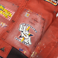 CLB XXIII red Carhartt work jacket featuring distressed patchwork, paint splatters, and Blind Love USA graphic patches.
