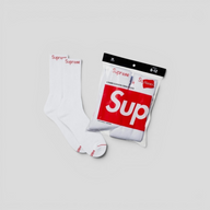 CLB XXIII white Supreme Hanes crew socks with red box logo on ribbed ankle, shown with original packaging.